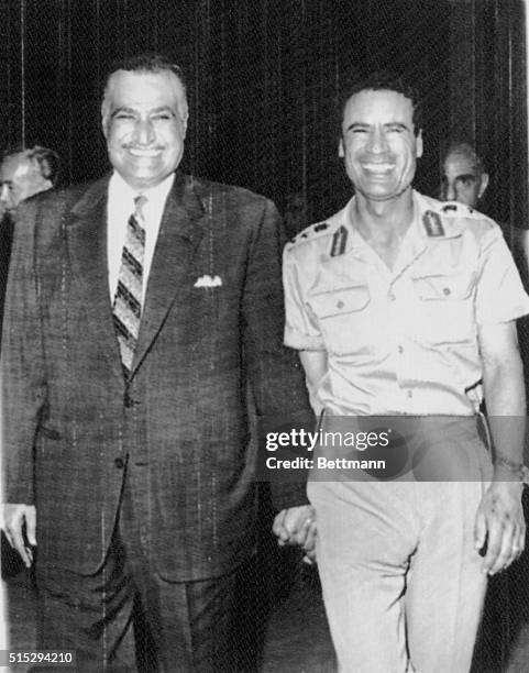 Hands clasped, United Arab Republic President Gamal Nasser and Libyan leader Colonel Muammar al-Qaddafi smile broadly as Nasser welcomes al-Qaddafi...
