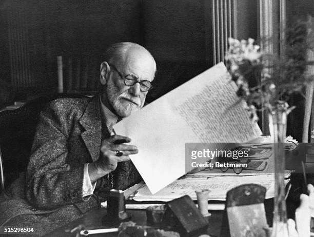 Sigmund Freud, 1856-1939, Austrian psychiatrist, in the office of his Vienna home looking at a manuscript.