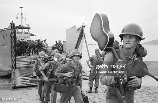 Qui Nhon, South Vietnam - Guitar slung over his shoulder, a trooper of the United States 1st Calvalry walks ashore from a landing craft. More than...