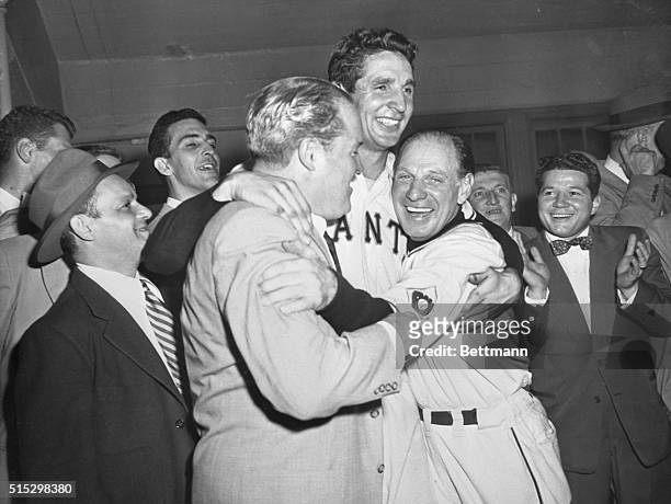 New York, NY- Owner of the Giants, Horace Stoneham, and manager Leo Durocher, hug hero of the game Bobby Thomson following his pennant-winning homer...