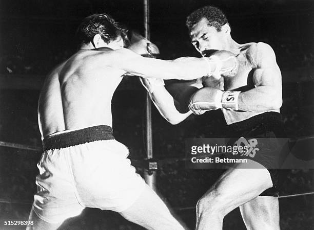 Mexico City, Mexico- World featherweight champion Sugar Ramos, in black trunks, and Mexican champion Vincente Saldivar trade blows during their match...