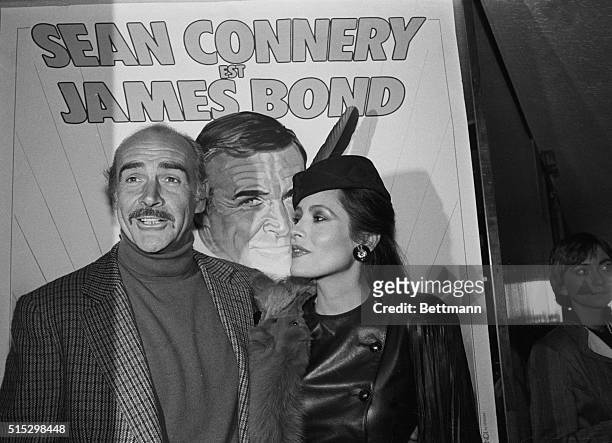 Paris, France- Actor Sean Connery and actress Barbara Carrera, posing 11/16 in front of a poster promoting the new James Bond film "Never Say Never...