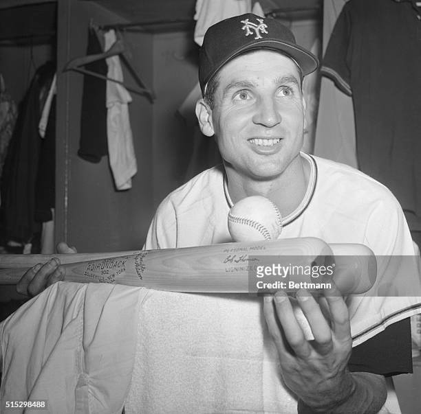 New York, NY- New York Giant center fielder Bobby Thomson happily balances on two bats the ball which was involved when he banged out the 1,000th hit...