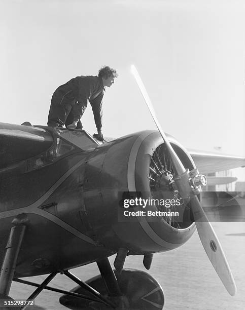 Amelia Earhart, , American aviatrix, first woman to cross the Atlantic Ocean in an airplane. She stands on top of her plane. Undated photograph.