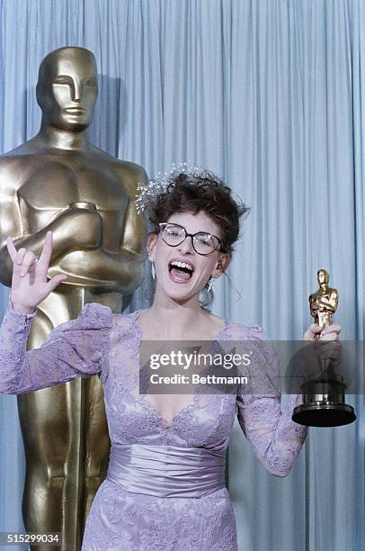 Los Angeles, CA-Actress Marlee Matlin holds her Oscar, which she recieved for Best Actress, as she signs "I love you" at the Academy Awards.