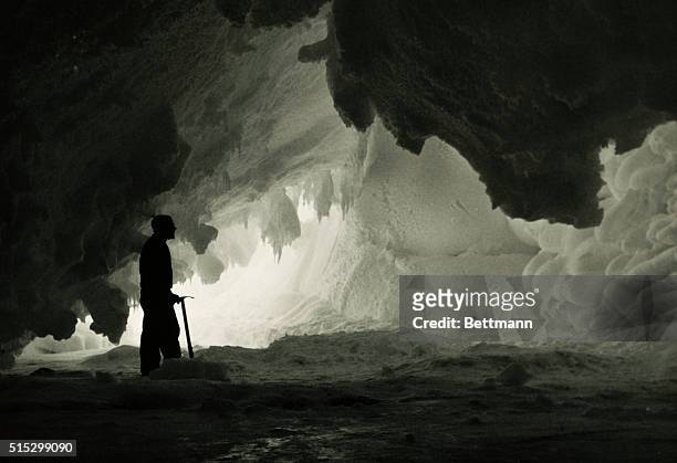 Antarctica: Interior of ice cave about 10 miles from McMurdo Station. A man with an icepick stands there. Undated photograph.