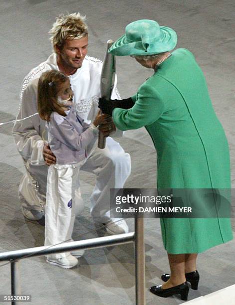 Britain's Queen Elizabeth II receives the Jubilee Baton from six-year old Kirsty Howard accompanied by British soccer player David Beckham during...