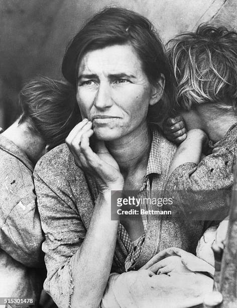 Poverty-stricken migrant mother with three young children gazes off into the distance. This photograph, commissioned by the FSA, came to symbolize...