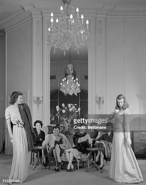 New York, NY-Two women model evening gowns at a Bergdorf Goodman in-store fashion show, as a group of prospective buyers watch. Undated photograph,...