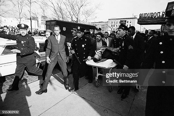 New York, NY- Two policemen carry stretcher bearing Negro nationalist leader Malcom X after he was downed by an assassin's bullets at a rally...