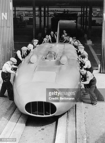 Workmen are shown here pushing the 34 foot "Thunderbolt," the famous racing car of George Esyton, out of the shops here, at the completion of its re...