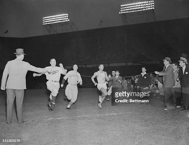 Dodger outfielder Ernie Koy beats Cincinnati Reds infielder Lee Gamble and Olympic gold medalist sprinter Jesse Owens during a 100-yard dash...