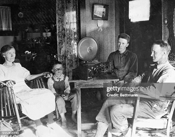 Family is shown gathered around a radio set. Undated photograph.