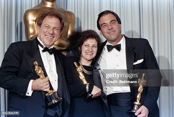 Los Angeles: Producer Arnold Kopelson , film editor Claire Simpson and director Oliver Stone hold their respective Oscars for Platoon at the Academy...