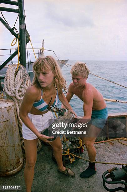 Young woman and man on board a Treasure Salvors boat, heave a piece of wreckage onto the boat, this is just one of the artifacts recovered from the...