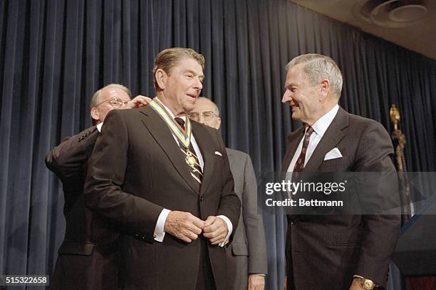 Washington, DC: President Reagan wears medal presented to him after his address to the Council of the Americas, May 12. At right is David Rockefeller.