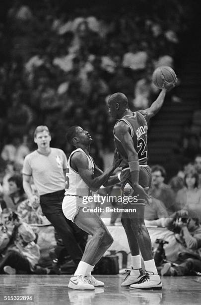 Sixers' David Wingate and Chicago's Michael Jordan are almost the same size-- 6'5" and 6'6"--Jordan stands tall as he holds the ball high under his...