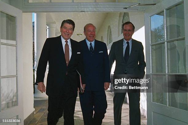 Washington, D.C.: Secretary of State George Shultz flanked by President Reagan and Vice President George Bush, leaves the Oval Office after Shultz...