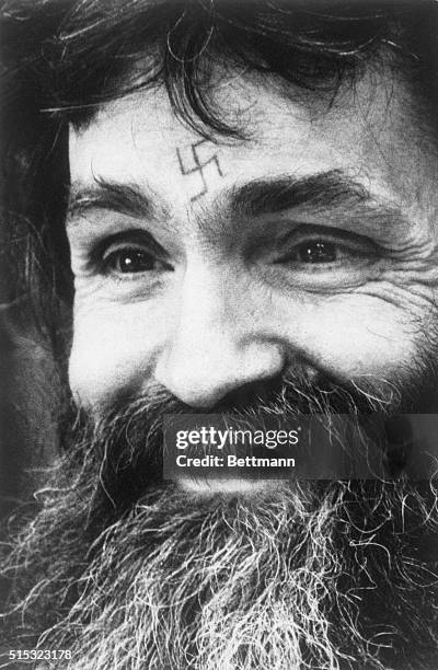 Charles Manson, with a swastika tattoo on his forehead, listens to the panel at his parole hearing.