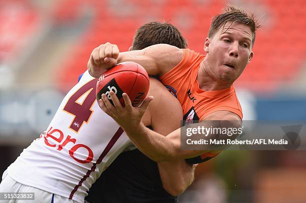 Toby Greene of the Giants handballs in the tackle of Ryan Bastinac of the Lions during the NAB Challenge AFL match between the Brisbane Lions and the...