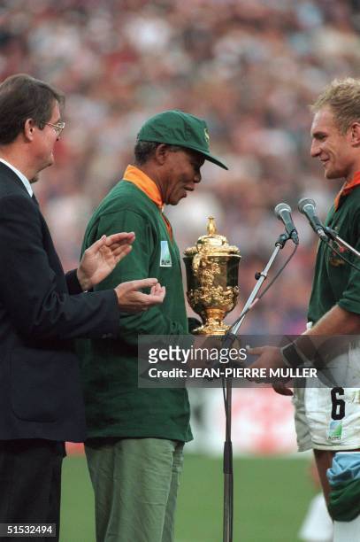 South African President Nelson Mandela congratulates Springbok skipper Francois Pienaar after handing him the William Webb Ellis trophy as Bernard...
