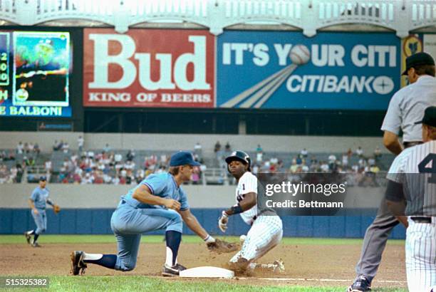 Kevin Seitzer of the Kansas City Royals can't hold on to the ball as Deion Sanders of the New York Yankees slides safely into 3rd in first inning...