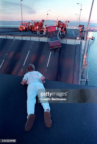 Linda Reed looks over the edge of collapsed bay bridge after running across the bridge to see if her husband was among the victims trapped when the...