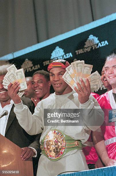 Heavyweight champion Mike Tyson flashes the $100,000 bonus given him by promoter Don King for knocking out Carl Williams in the first round of their...