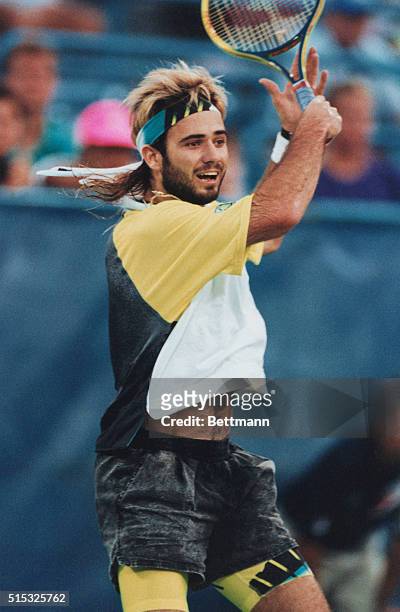 In his usual non-traditional tennis clothung, Andre Agassi, sporting a bread and longer hair, in action at the US Open. Photo by Jon Simon/Bettmann...