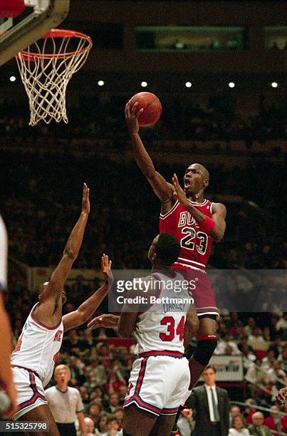 Michael "Air" Jordan soars over two New York Knicks, Sidney Green and Charles Oakley as he drives for two points during their NBA Playoff Game here...