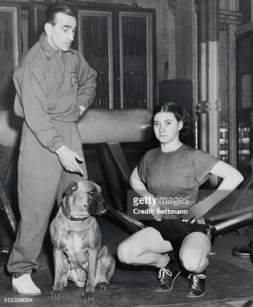 Mickey Wood puts 18-year old Barbara Buttrick through limbering up exercises before a light sparring bout with her at his Mayfair gymnasium. Wood and...