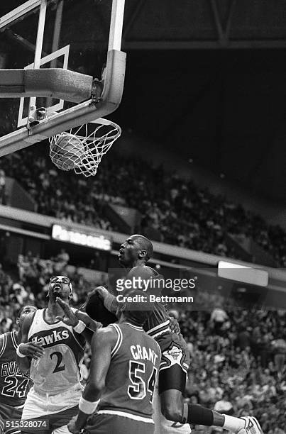Bulls' Michael Jordan, top center, watches his shot go through the basket, while being held in the arms of Hawks' Cliff Levingston, partially hidden...
