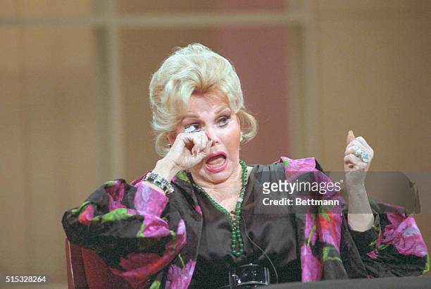 New York: Zsa Zsa Gabor dabs at her eye as she appears on the Donahue Show here. Earlier in the week, Ms. Gabor was sentenced to three days in jail...