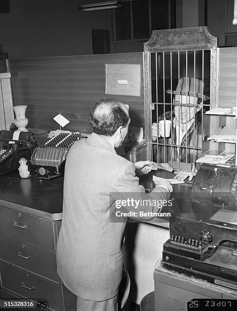 Flushing, Queens- Coffee in hand, depositor Frank Fencl has a contented smile for chief teller John De Phillips as he transacts his business at the...