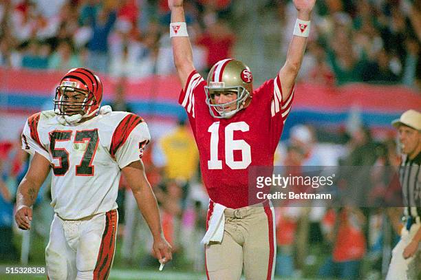 49ers quarterback Joe Montana raises his arm in celebration after throwing a touchdown pass to Jerry Rice in the fourth quarter. Bengal Sam Kennedy...