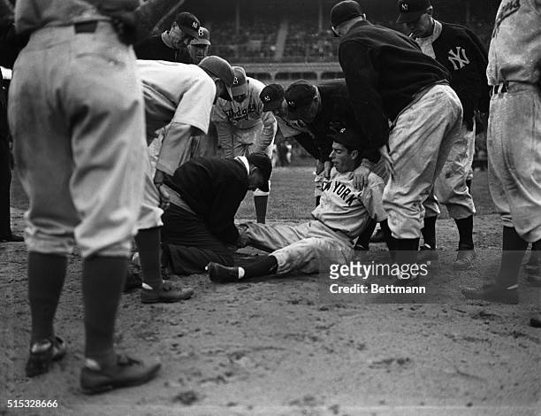 Joe DiMaggio, shining star of the New York Yankees baseball team, is shown here surrounded by teammates and opponents after he had injured his right...