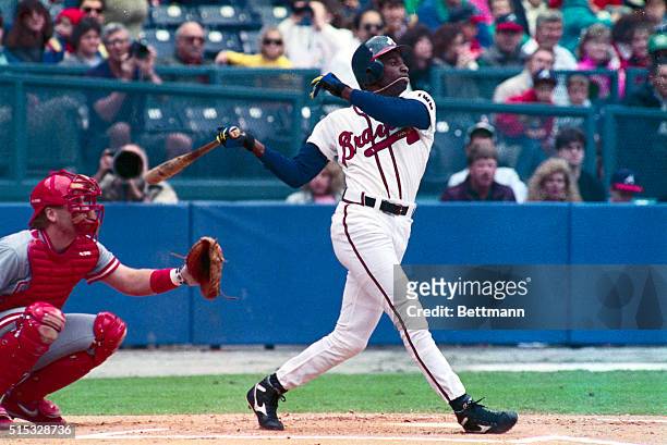 Braves' outfielder Deion Sanders , who is known for his flamboyant football talents, gets his necklace caught in his mouth as he slams a triple to...