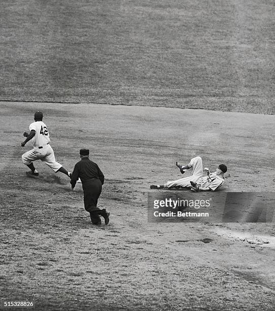 Jackie Robinson of the Dodgers heads for third base after stealing second base on Joe Garagiola's throw to Red Schoendienst, covering second base for...