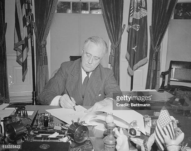 Washington, DC.: President Franklin D. Roosevelt is shown signing the historic Lend-Lease Bill at the White House in Washington, DC. He put it into...