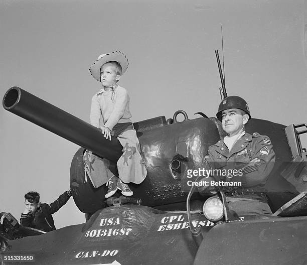 Stephen Jost, 6-year-old son of Major Harry Jost of Fort Benning, sits on the muzzle of a gun of an Army M45 heavy tank while, Sgt. Herman R. Hill,...
