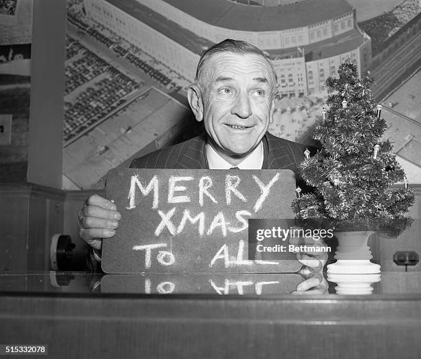 Casey Stengel, manager of the world champion New York Yankees, takes time out during a visit to the Yankees' business office to extend a Christmas...