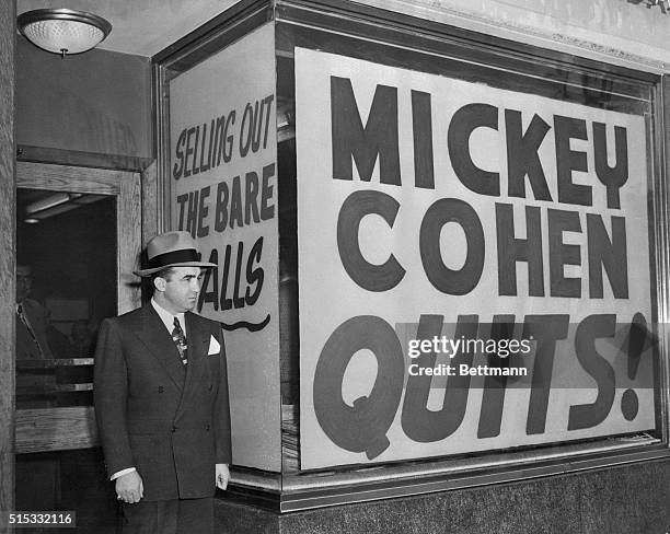 Mickey Cohen stands by the signs in the windows of his exclusive Sunset Strip men's shop. Cohen was forced to sell his place to meet the $75,000 bail...