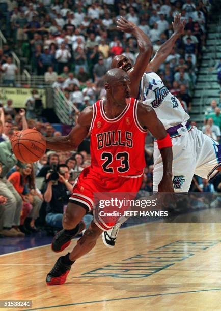 Michael Jordan of the Chicago Bulls sticks out his tongue as he goes past Bryon Russell of the Utah Jazz 11 June 1997 during game five of the 1997...