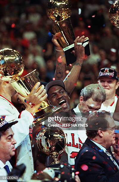 Chicago Bull player Michael Jordan is surrounded by NBA Championship trophies after his team defeated 13 June 1997 the Utah Jazz 90-86 to win the...