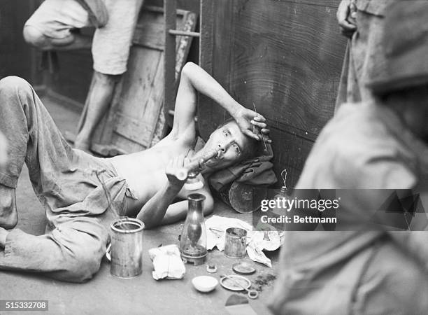 Aboard opium boat off Hong Kong: The addict is all set to enjoy his pipe dream. Beside him is the entire layout, can of peanut oil, lamp, wire for...