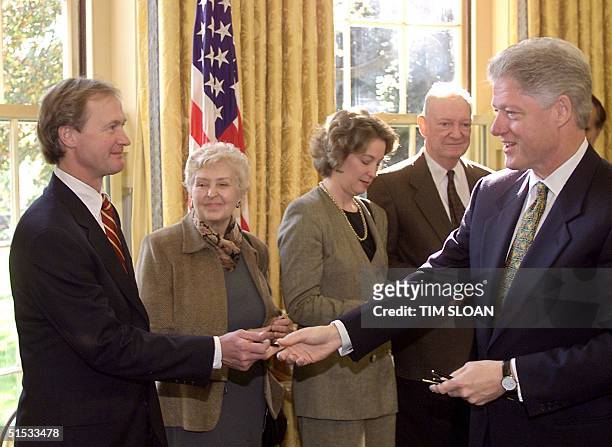 President Bill Clinton hands Senator Lincoln Chafee a pen after signing S.1652 designating the Old Executive Office Building next door to the White...