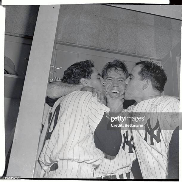 Yankee shortstop Phil Rizzuto and catcher Yogi Berra plant kisses on the beaming face of outfielder Hank Bauer, who made the sensational 3rd out...