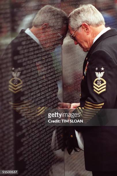 Freddie Chase Sr,a 41 year retired US Navy veteran leans against the Vietnam memorial wall in front of the name of his son 11 November, 1999 in...