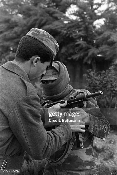 Dressed in guerrilla gear, a young Fatah member receives instruction on how to handle his weapon.