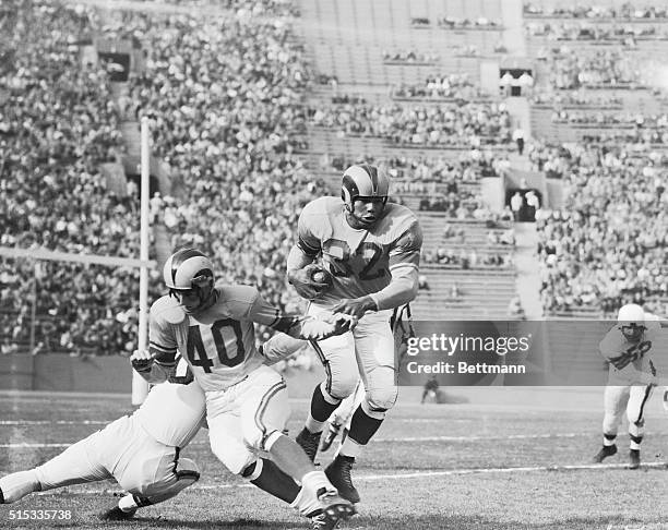 Elroy Hirsch, the Los Angeles Ram's end, blocks out a Cleveland Brown tackler here, as the Rams' "Deacon" Dan Towler, goes for ten yards on the...